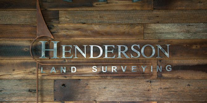 Henderson Land Surveying Metal sign hung up on a shiplap wall